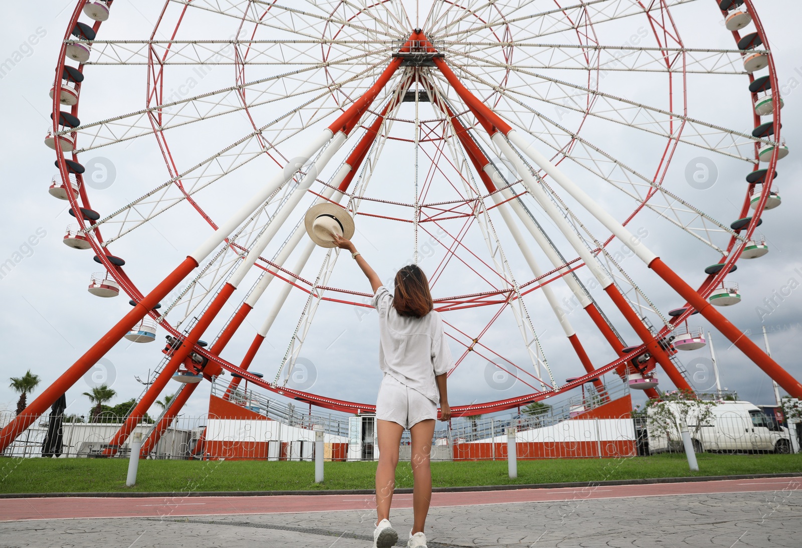 Photo of Young woman near Ferris wheel outdoors, low angle view