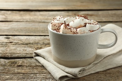 Photo of Delicious hot chocolate with marshmallows and cocoa powder in cup on wooden table, closeup. Space for text