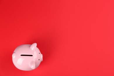 Photo of Pink piggy bank on red background, top view. Space for text